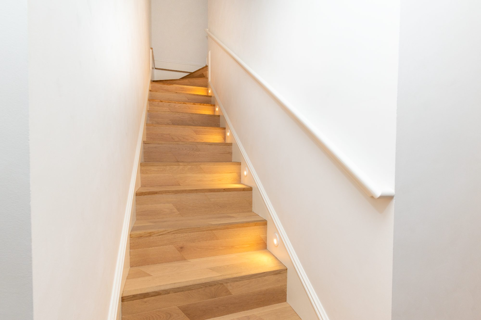 Oak staircase with recessed lights set into the wall at each step
