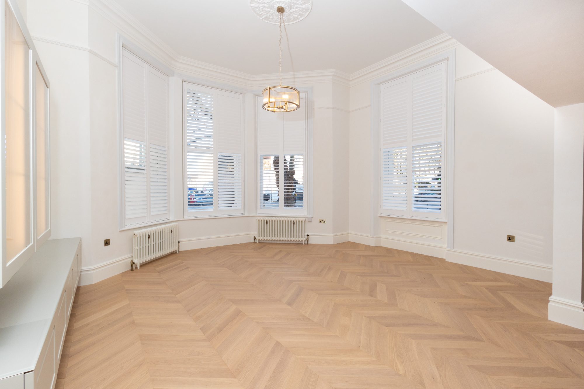 Reception room with chevron oak floor, shutters and built-in low cabinetry