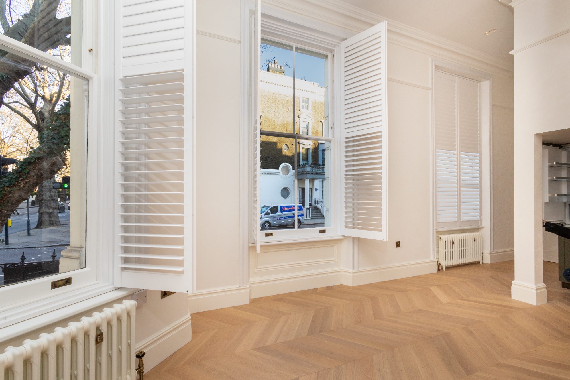 Sash windows with full-height interior shutters folded back, chevron oak floor