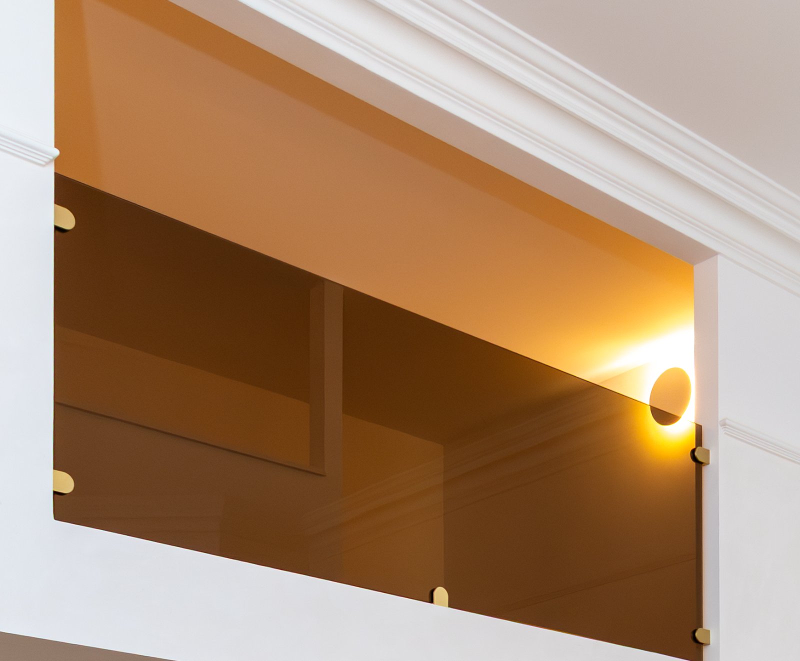 Bronze glazed screen held on brass fixings above a panelled wall
