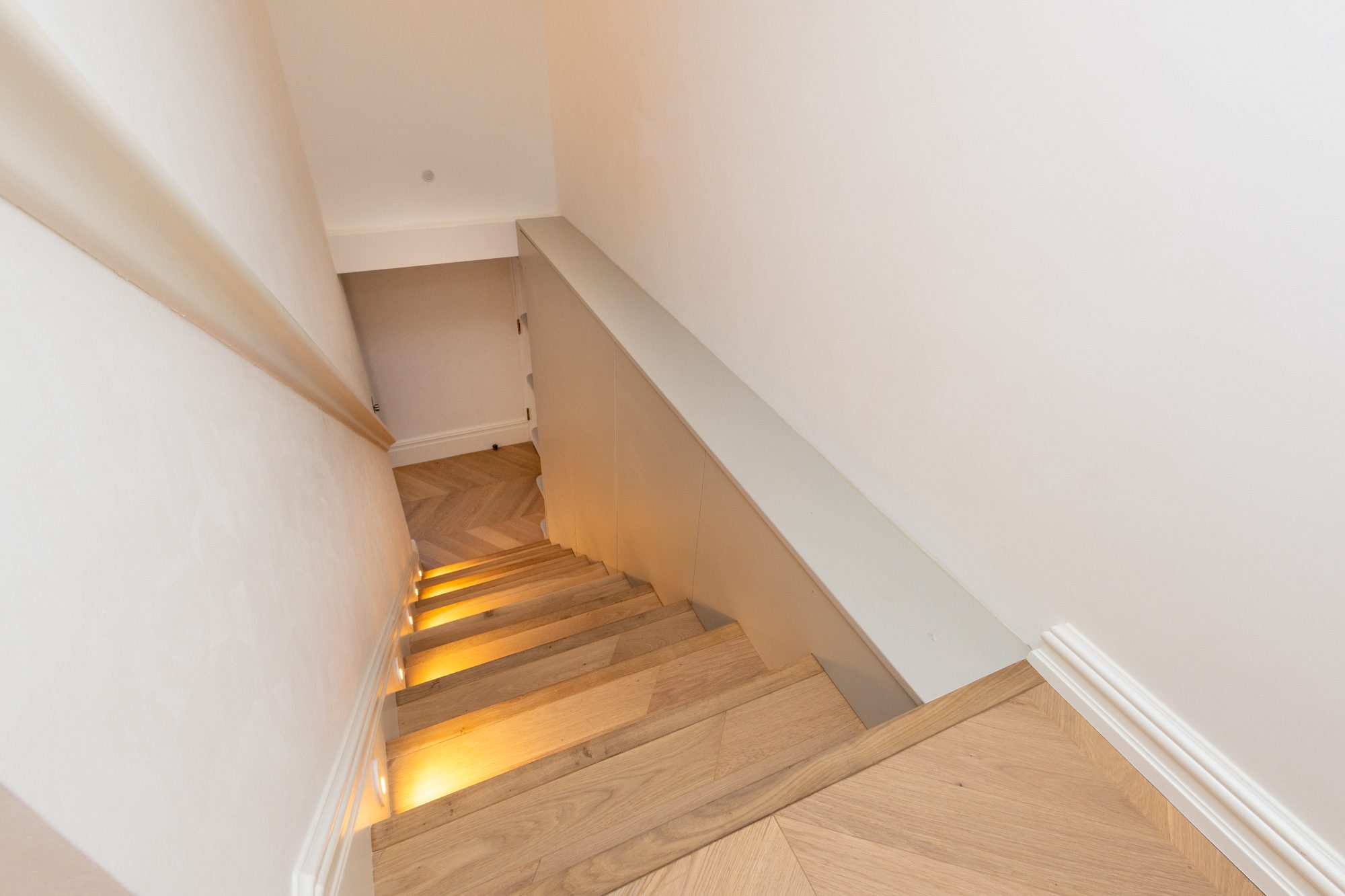 Looking down the oak staircase to the chevron floor below