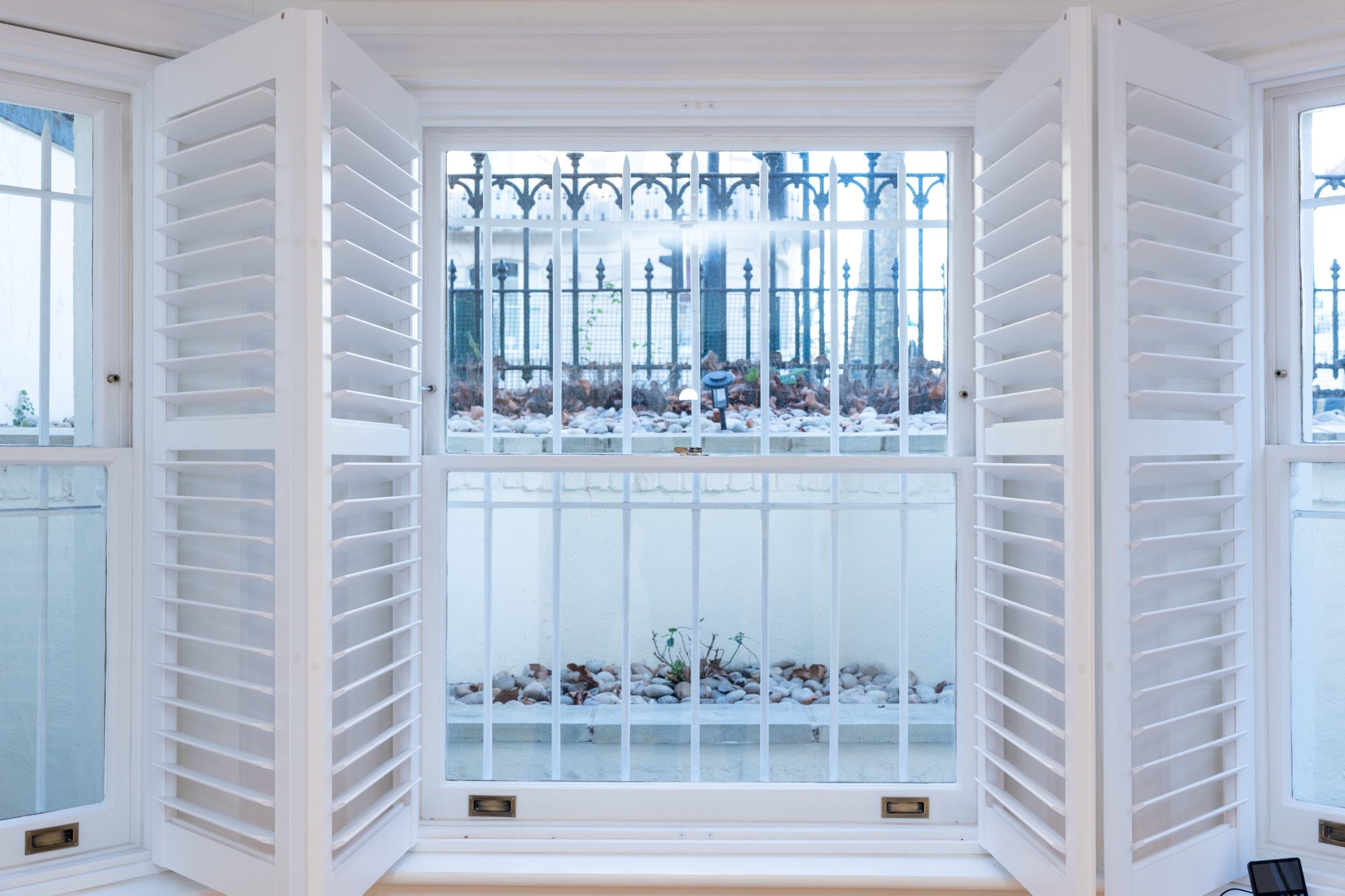 Shutter panels open across a bay window at lower ground level
